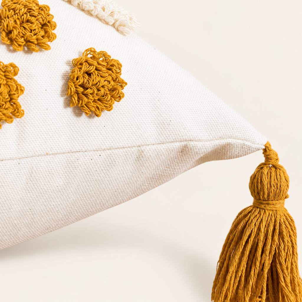 Close view of tufted ochre loops, cream canvas corner seam and knotted tassel