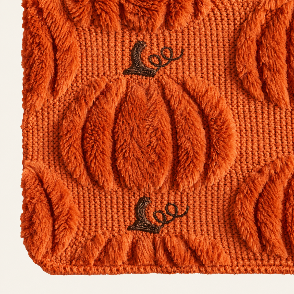 Close view of the caramel runner's raised pumpkin motif, ribbed knit and dark stem embroidery
