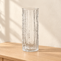Tall textured clear glass vase against a warm neutral backdrop